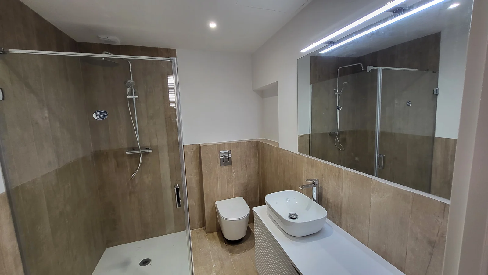 Baño acabado con ducha, lavabo y espejo iluminado