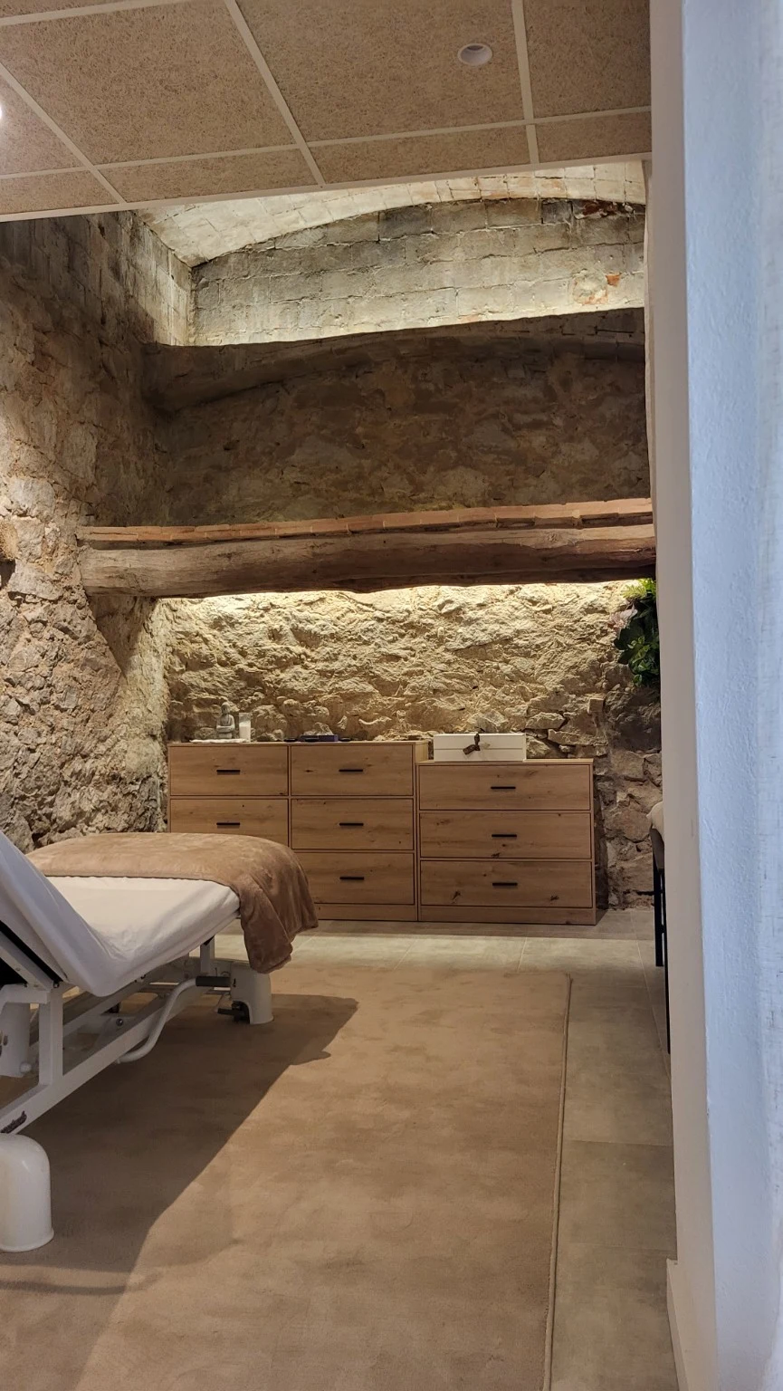 Sala de tratamientos con paredes de piedra e iluminación indirecta sobre las vigas